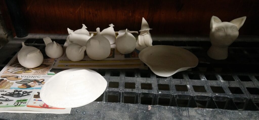 Bisqued awaiting glazing chickens, wall pocket, gnome, soap dish and cat head